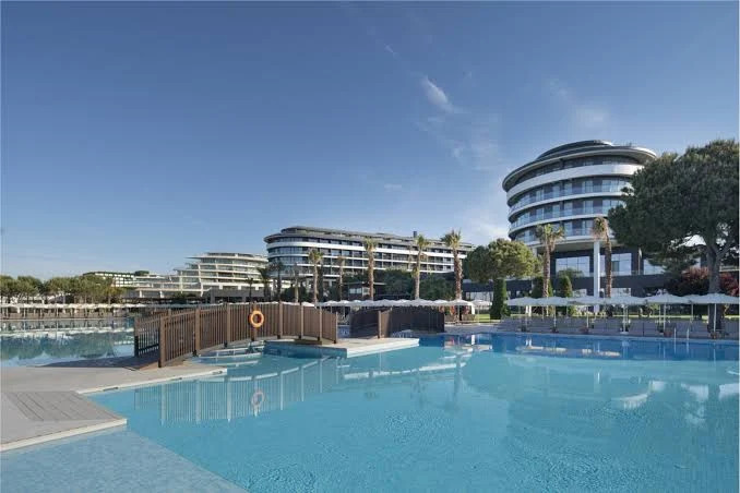 Voyage Belek Hotel transfer service by the luxury resort pool after Antalya Airport arrival.